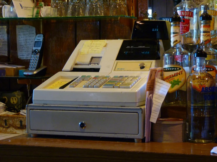 old cash register machine with various liquors and glasses on shelves