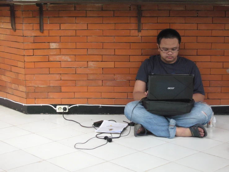 a man on a laptop sitting on the floor