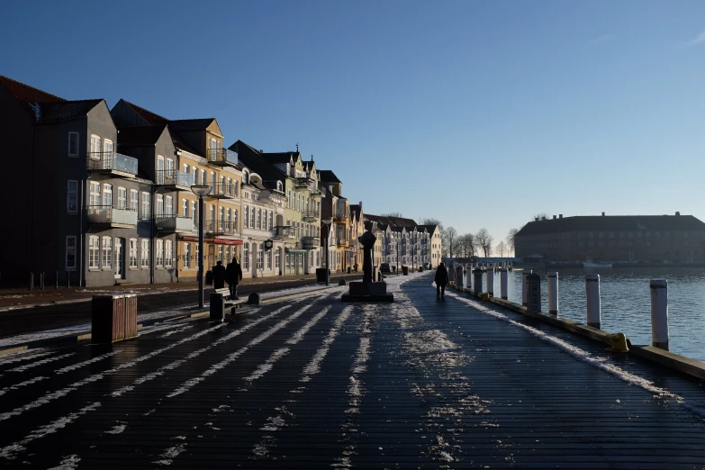 the sidewalk has long buildings along the water