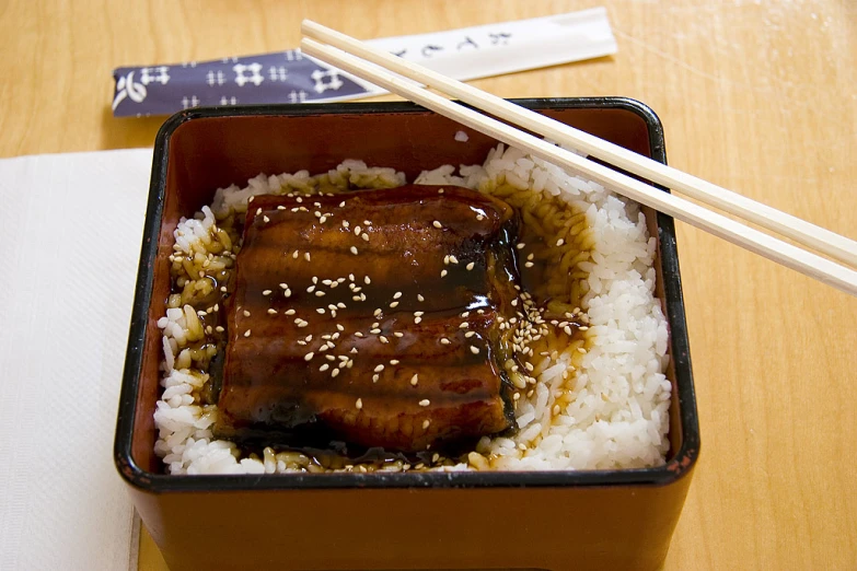 some food sitting on top of a white plate with chopsticks