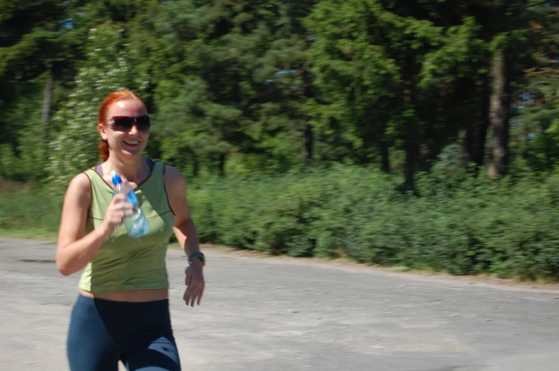 a woman in sunglasses is running while holding a water bottle