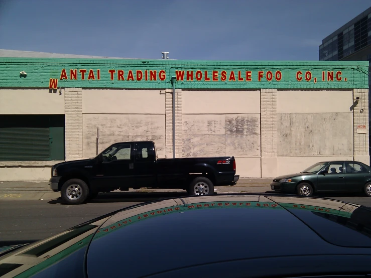 two cars sit outside a building with a large sign