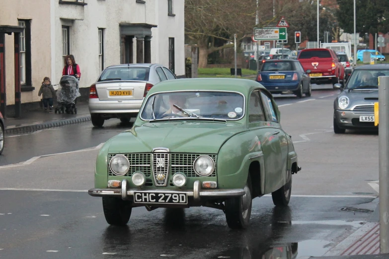 there is a small green car driving down the street