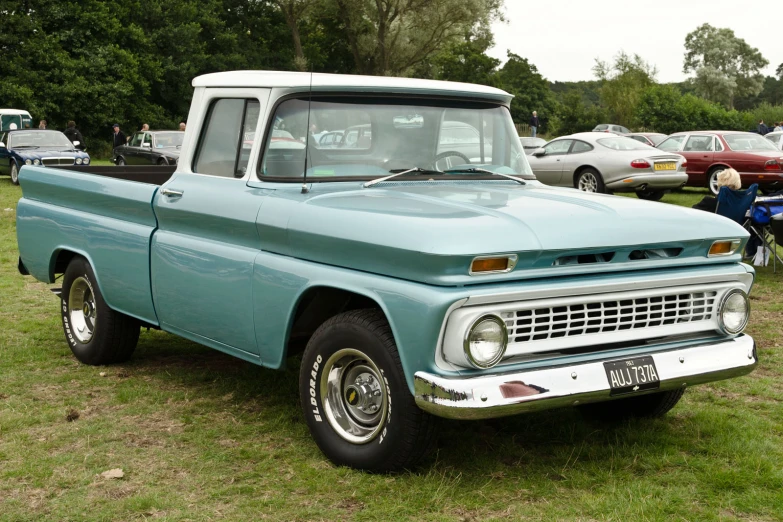 a green pick up truck parked on top of a grass field