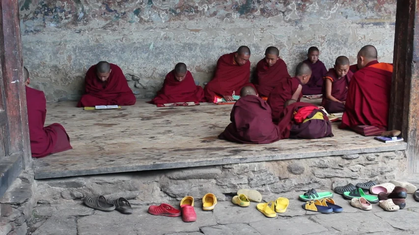 a group of monks in robes sit around a bed