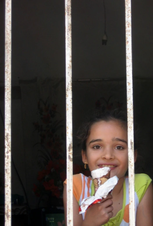 a  eating food behind bars of a building