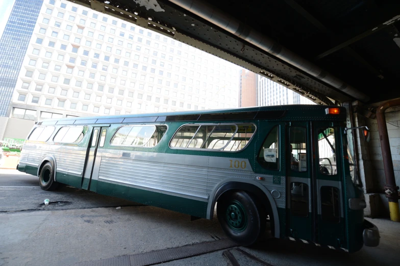 a green and white bus is parked near a tall building