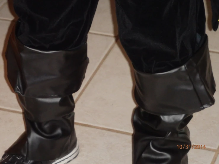 the man in the leather suit and boots is standing on a tiled floor