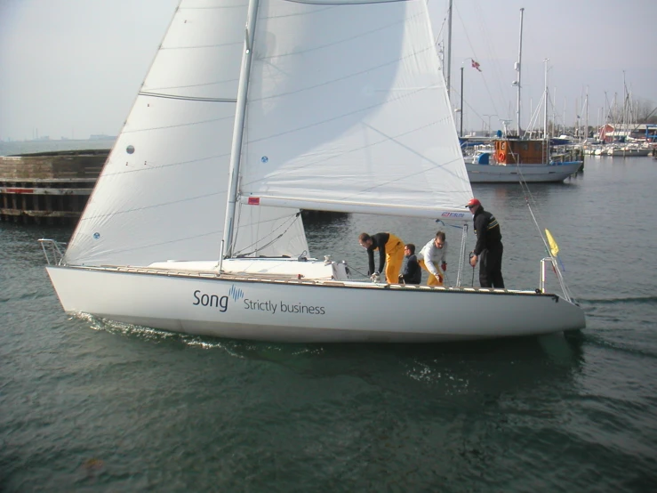 a small white sailboat with three people on board