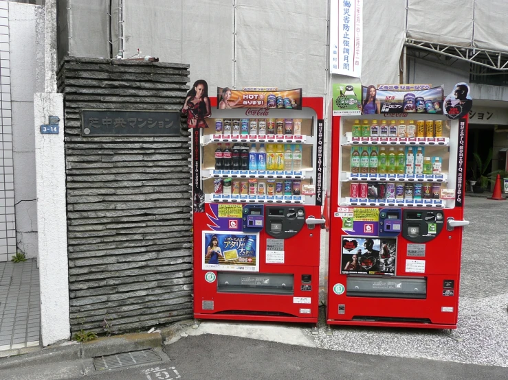 the woman is standing next to two red vending machines