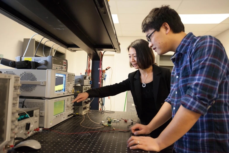 two young people looking at wires that are on a cabinet