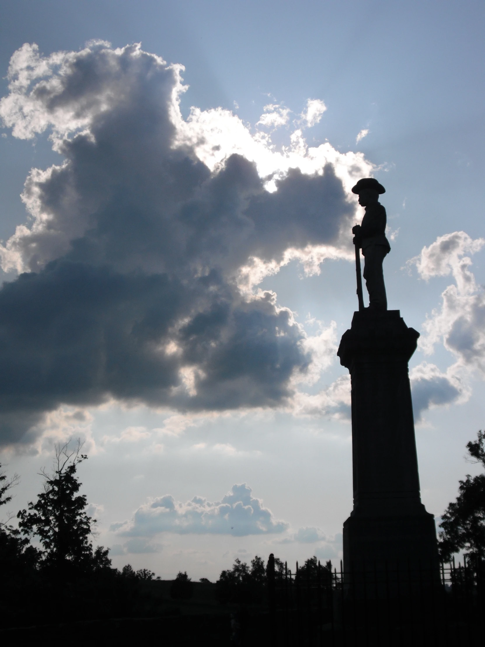 a statue under cloudy skies with dark clouds