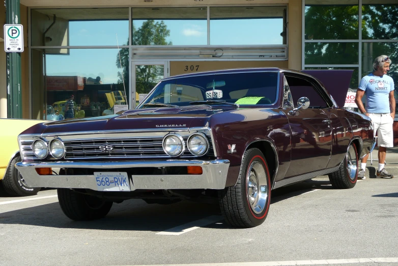 an old style maroon car parked in a parking space