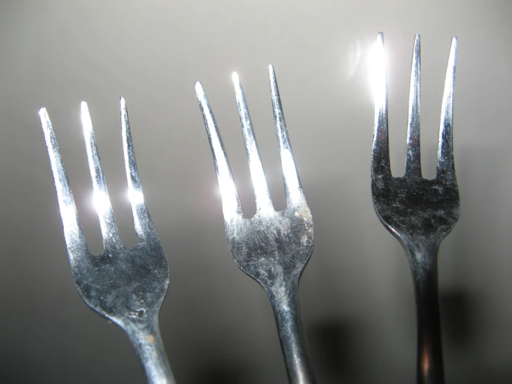 three forks and silver are set side by side