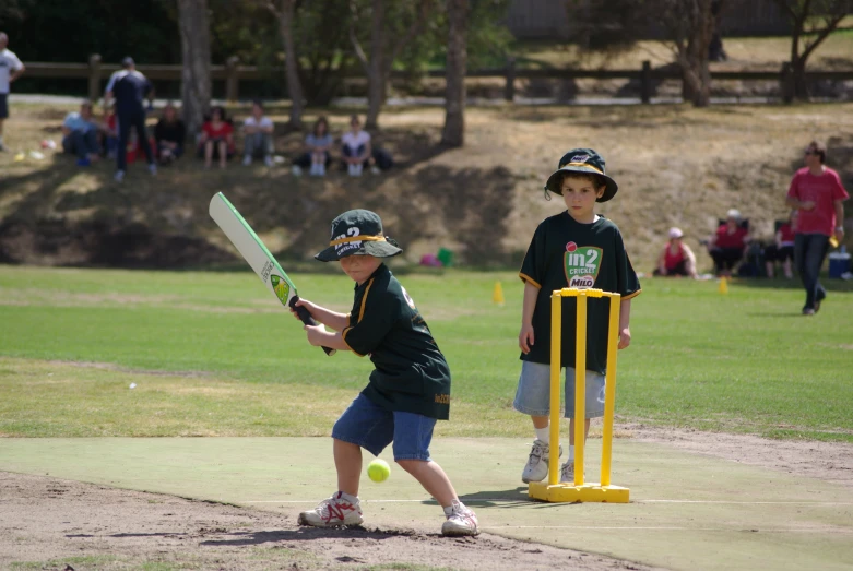 two boys wearing hats playing t - ball