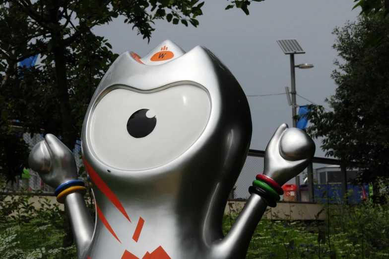 a large metallic cat statue next to a green field