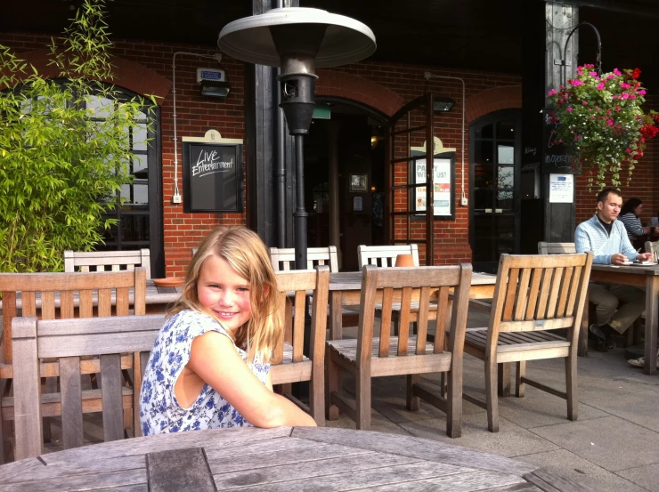 a child is sitting outside of a restaurant at a table