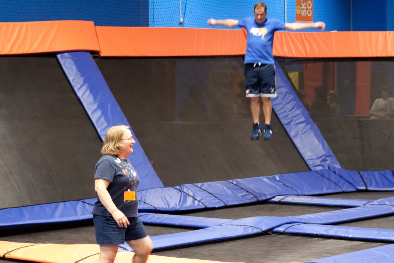 a man and woman on trampoline in an indoor playground