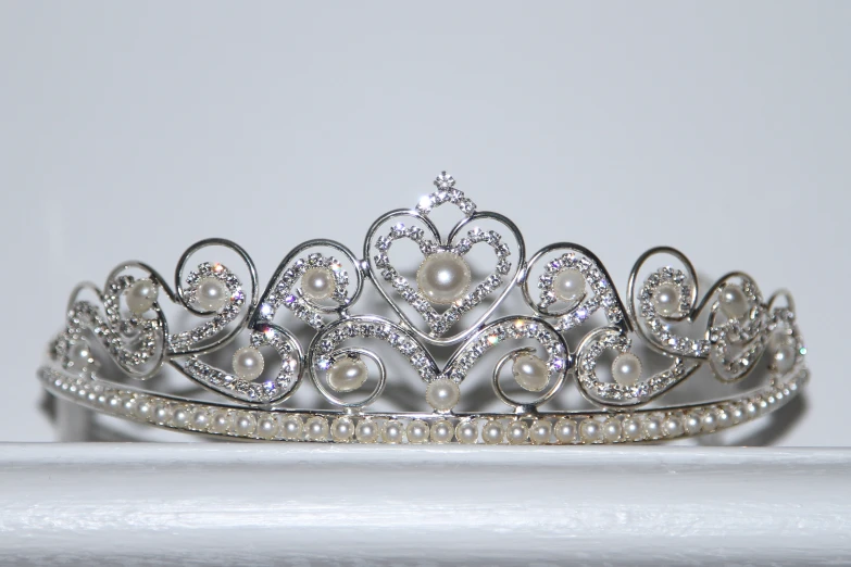 a tiara on a white surface with pearls