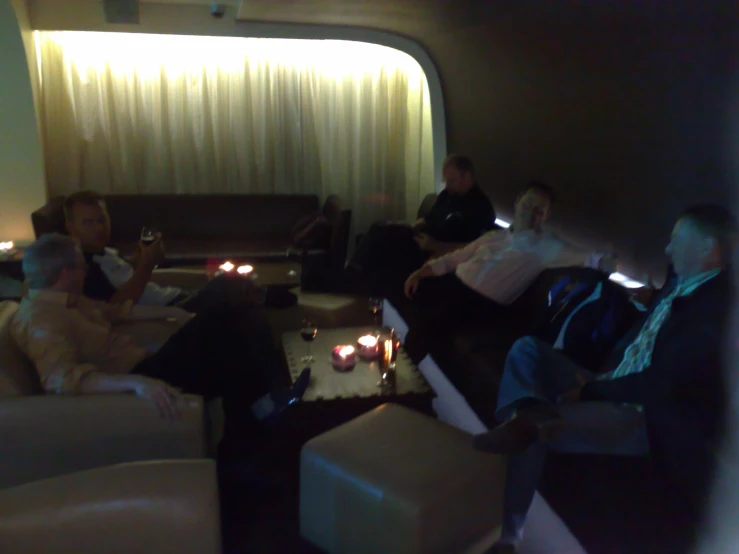 people in the living room relaxing on couches and a table with candles