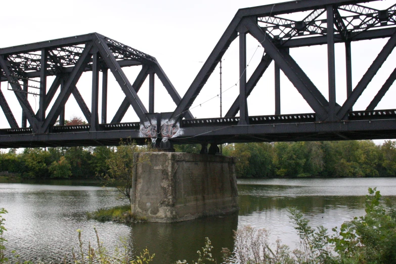 an old railroad bridge crossing a river in an area with trees