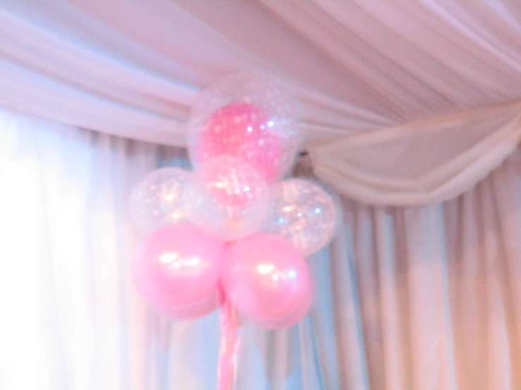 pink balloons floating on top of a table in front of curtain