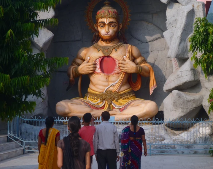 several people stand in front of a giant statue