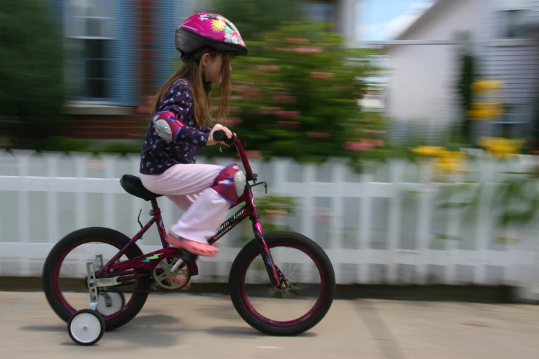 a small child in full helmet riding a little pink bike