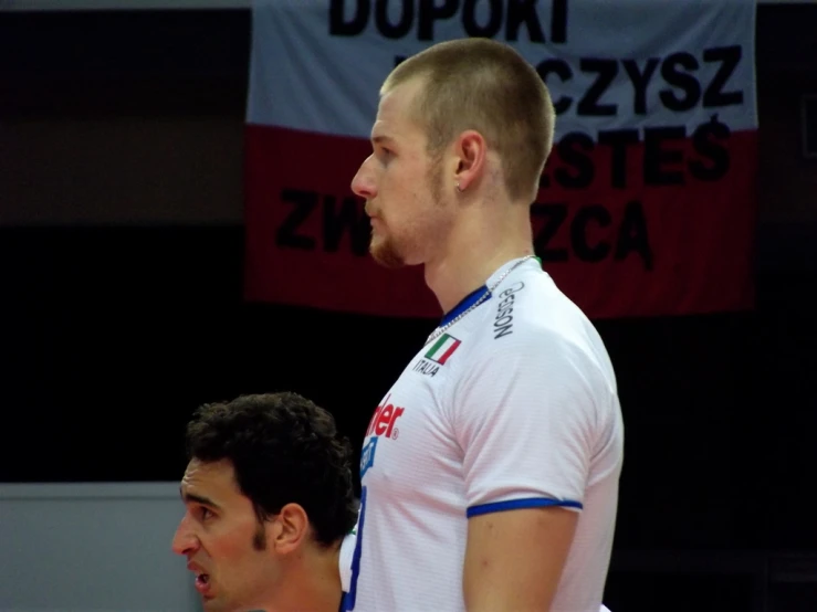 a male professional tennis player with a shaved head looks on