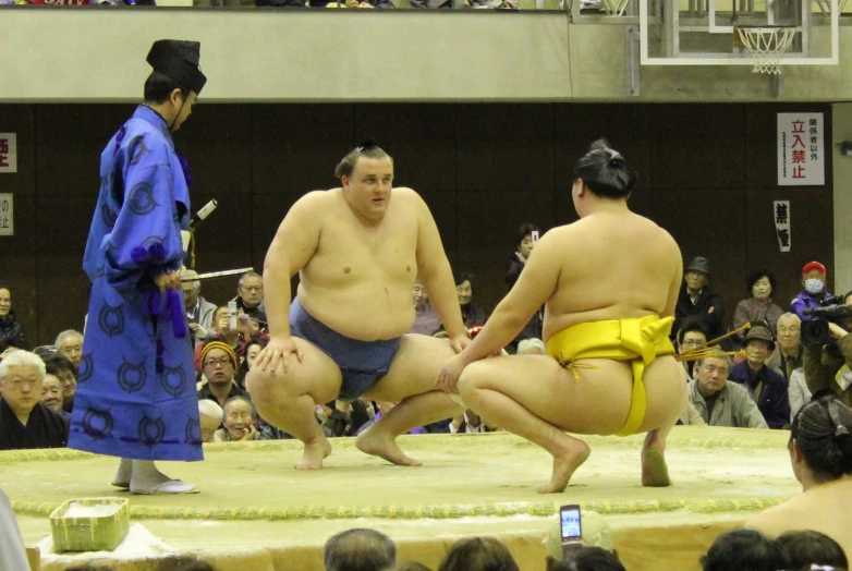 sumo wrestlers in sumo ring waiting for their opponent to strike