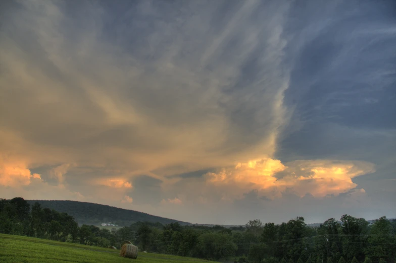 a sky with some clouds over a green field