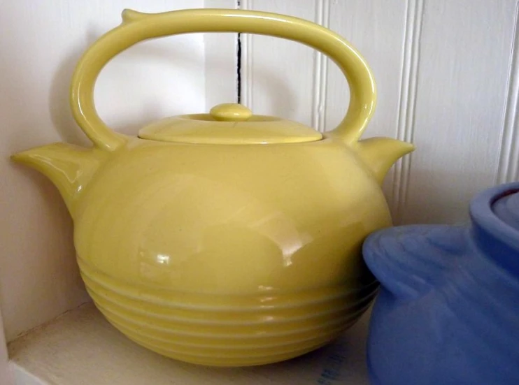 a yellow kettle on top of a white shelf