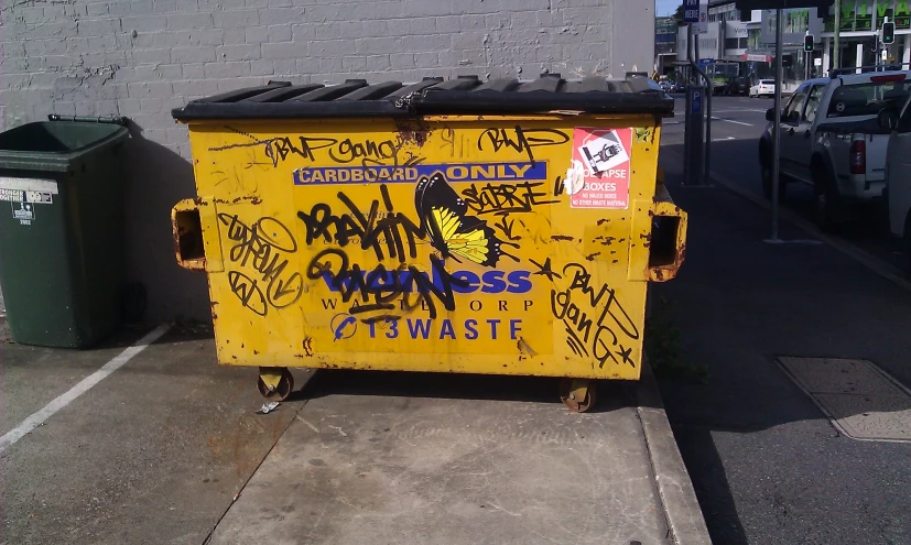 a trash can covered in graffiti on the side of a road