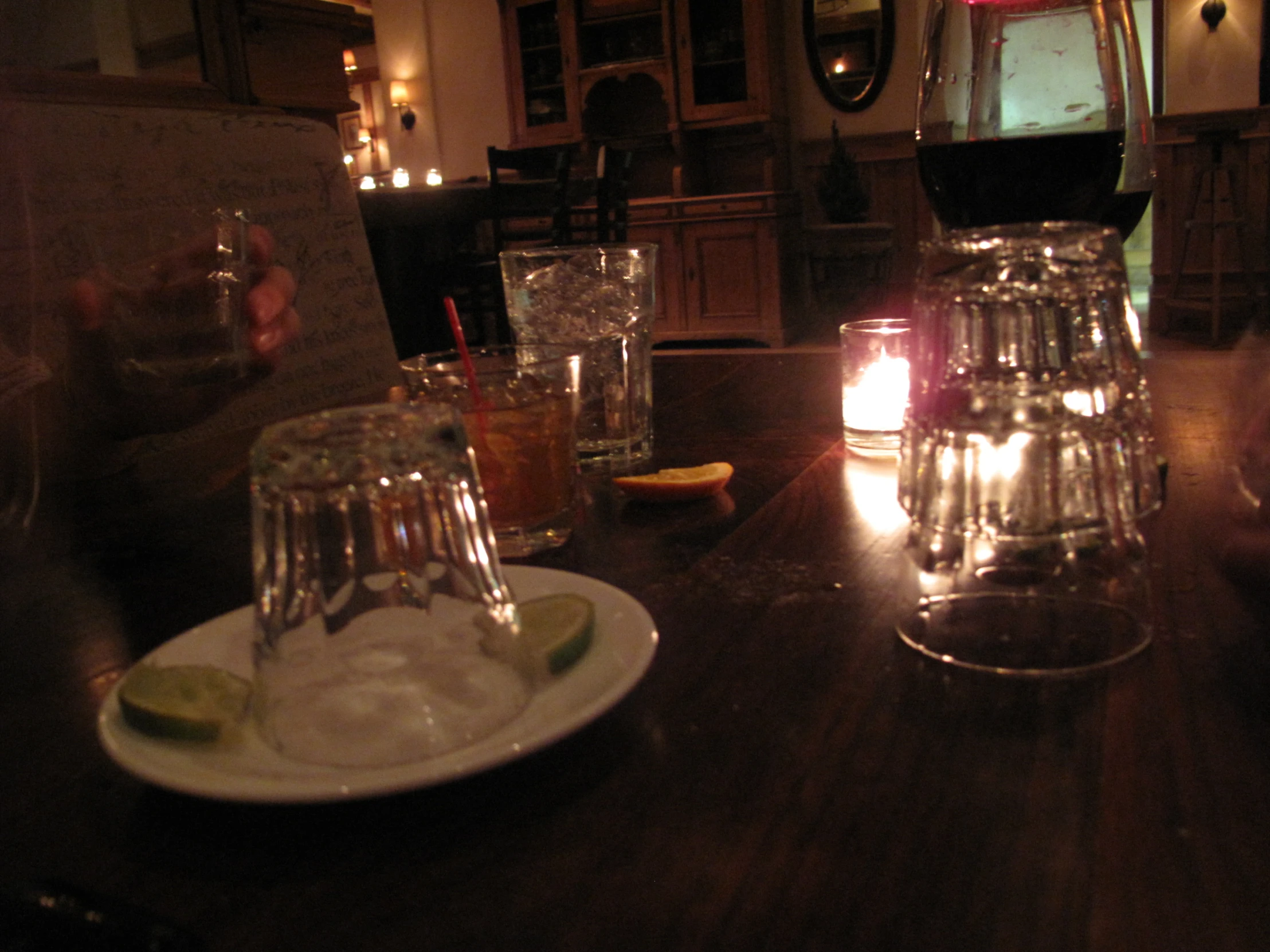 glasses on a table with candlelight inside a room