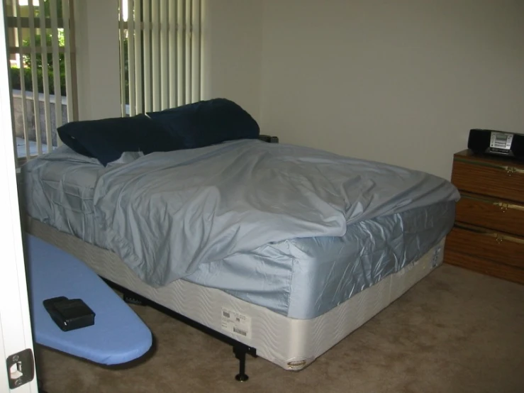 a small bedroom with a bed with a sheet on it and a surfboard under it