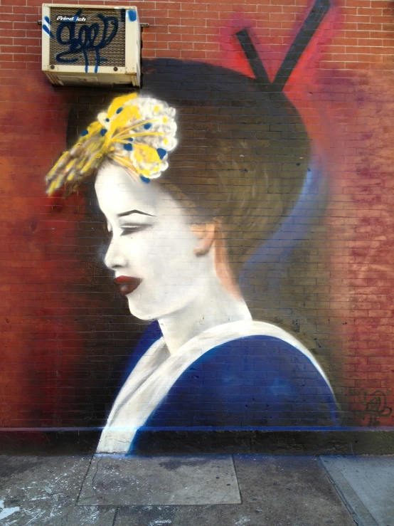 painting of a lady wearing a hat on a brick wall