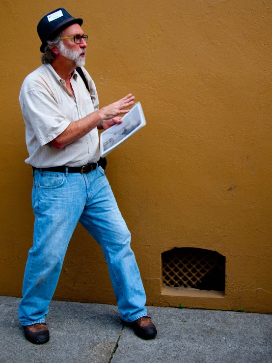 man walking down the sidewalk in front of a yellow wall