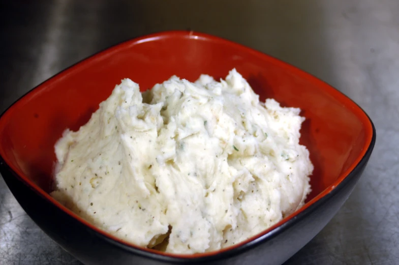 a red bowl full of mashed potatoes with herbs