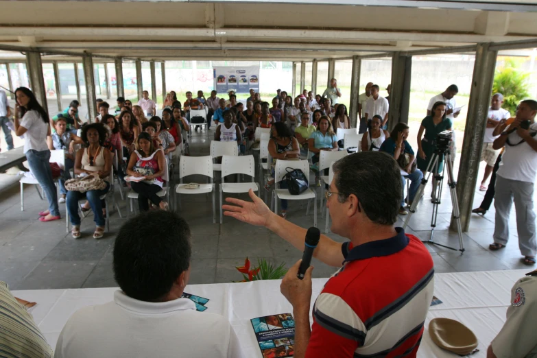 man standing on chair speaking to a group of people