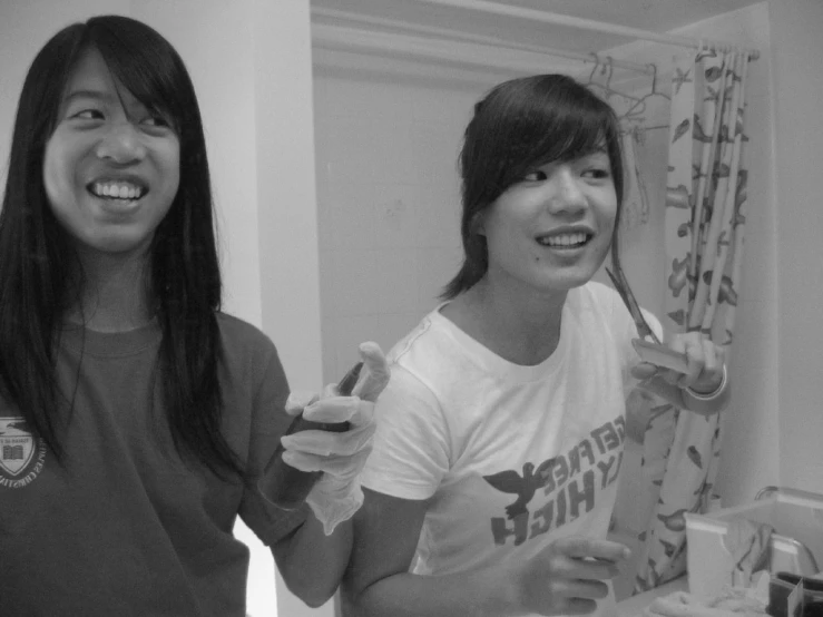 two girls with toothbrushes looking at their reflection in the mirror