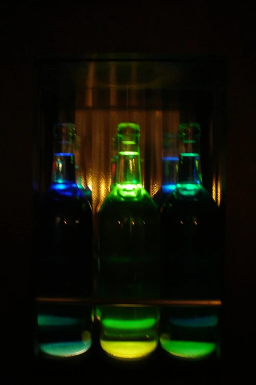 three glowing bottles in front of black background