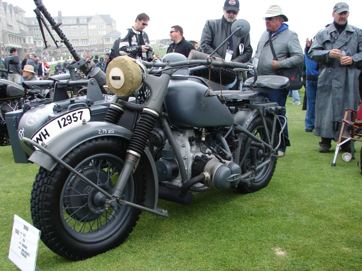 an old fashion motorcycle is parked near a group of people