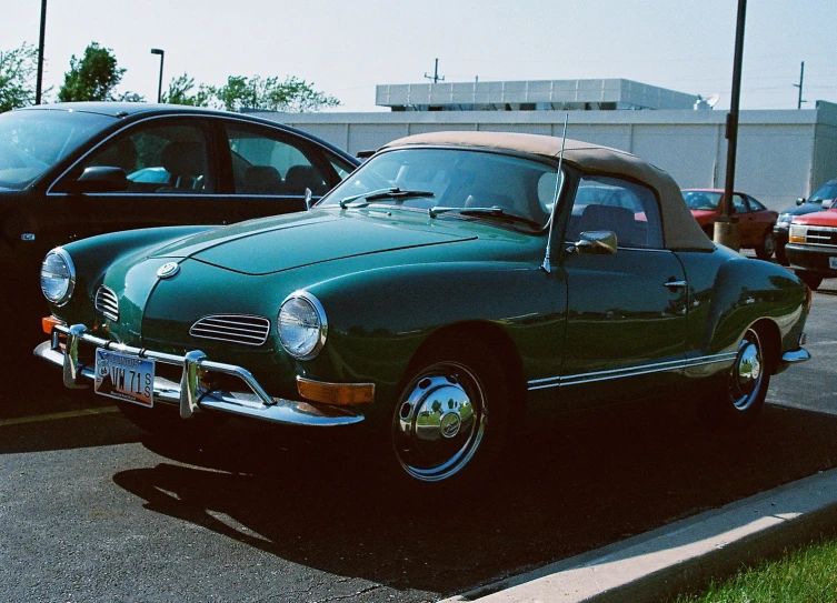 an old green classic car sitting in the parking lot