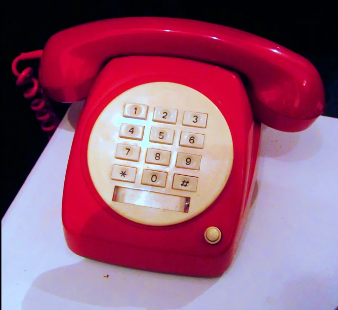 a red phone is on display on a counter