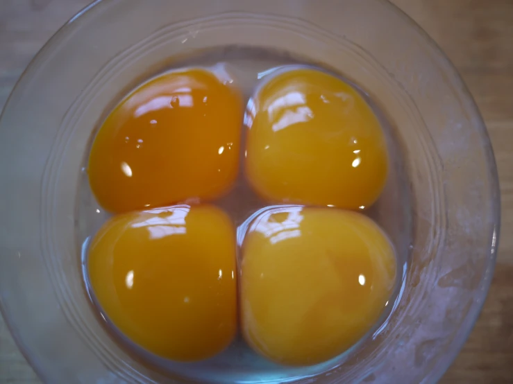 four eggs in a bowl sitting on the floor