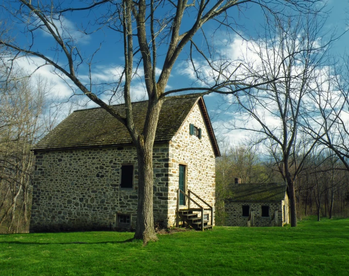 old stone house in the middle of grassy area