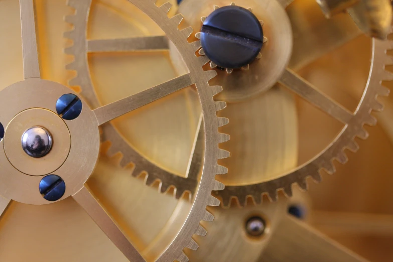 the gears on an intricate clock are gold and black