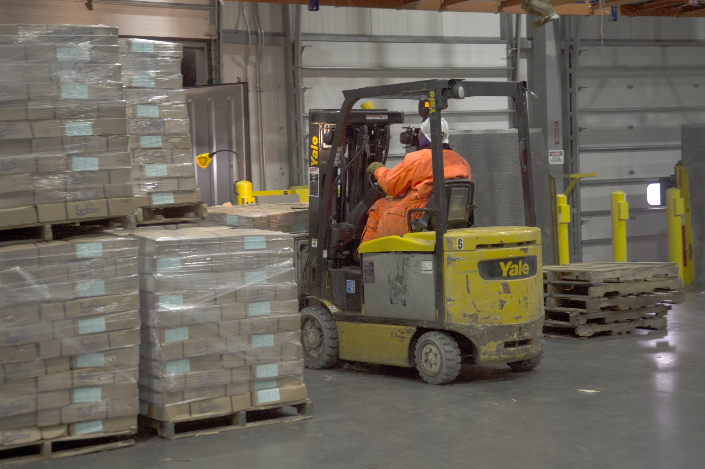 a person with orange jacket on and pallets