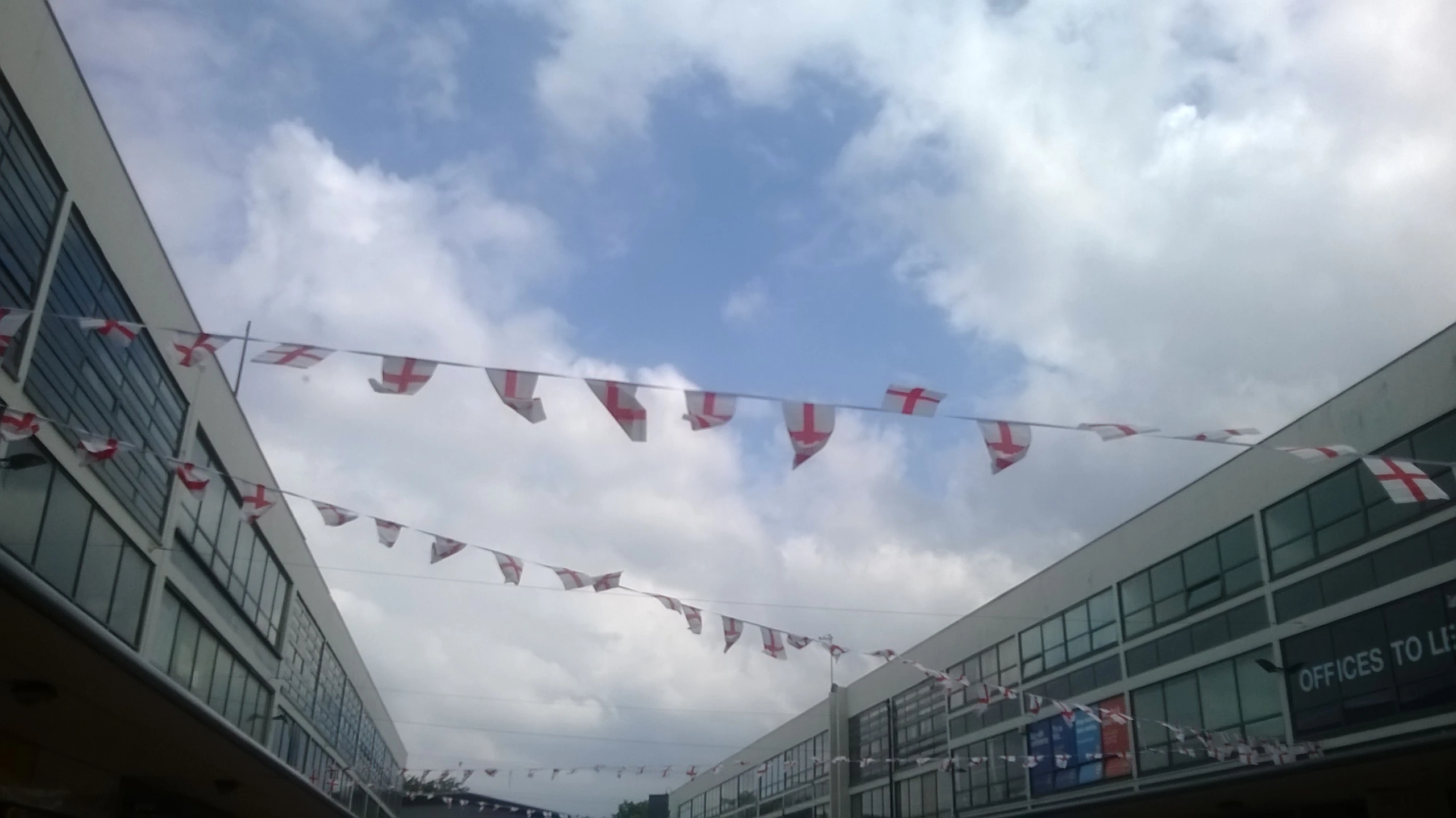 flags hanging from a line over street next to buildings