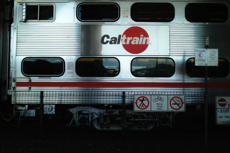 a silver train that is next to a fence